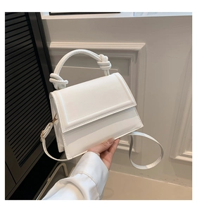 Détail d'un sac à main en cuir blanc avec poignée nouée et bandoulière réglable