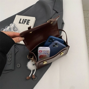 Retro dark brown leather crossbody bag with spacious interior and plush charm accessory
