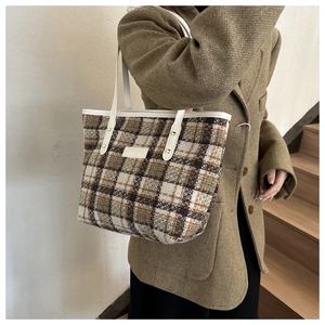 Detailansicht der Vintage-Karo-Struktur aus Tweed mit weißem Ledergriff und Nietenbesatz