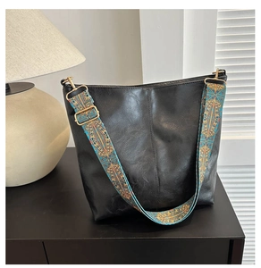 Detail of black leather tote bag featuring a colorful bohemian jacquard wide shoulder strap