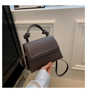 Détail du sac à main marron foncé avec poignée nouée et texture en cuir PU lisse