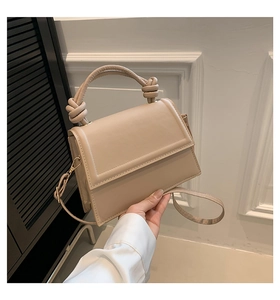 Détail d'un sac à main beige en cuir avec poignée nouée et bandoulière réglable