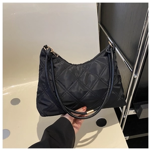 Close-up of black quilted nylon crescent bag with elegant gold metal ring hardware