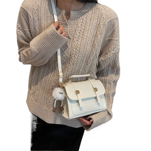 Retro cream crossbody bag with gold buttons and plush eye charm shown on a model