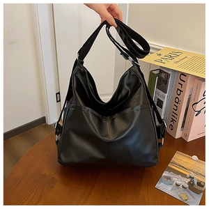 Detail of a large black matte PU leather hobo bag with adjustable strap on a wooden desk