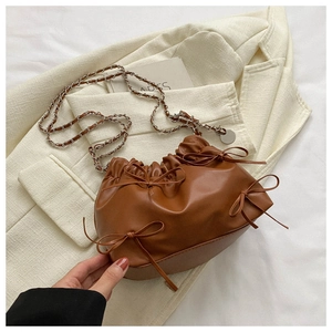 Nahaufnahme der braunen Falten-Handtasche mit Schleifen und silberner Kettenschulterkette
