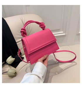 Détail du sac à main magenta avec poignée nouée et finitions métalliques dorées