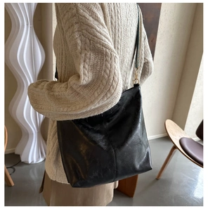 Macro detail of the black tote bag showing smooth leather texture and stitching