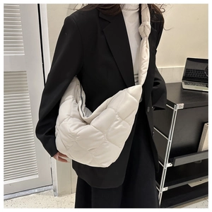 Detail of white quilted hobo bag with distinctive shoulder strap knot and soft texture