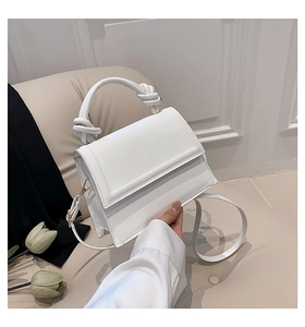 Détail du sac à main blanc minimaliste avec poignée nouée moderne et boucles dorées