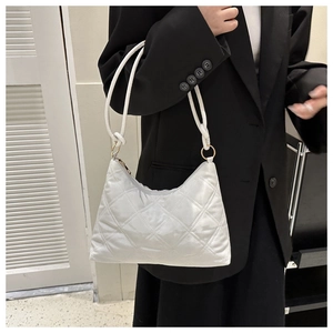 Detail of white quilted handbag with diamond pattern and gold metal ring connectors