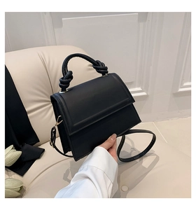 Détail de la poignée nouée d'un sac bandoulière noir mat avec des ferrures dorées