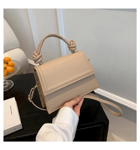 Détail d'un sac beige structuré avec poignée à nœud tissé et finitions métalliques dorées