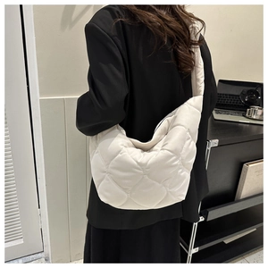Quilted off-white puffy crossbody bag shown worn by a model in a modern office setting