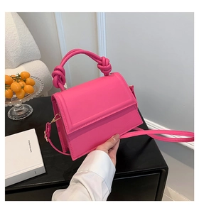 Vue détaillée du sac à main rose avec poignée nouée, rabat aimanté et bandoulière