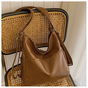 Detail of vintage brown hobo bag with front pocket and adjustable strap on rattan chair