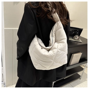 Detail of white quilted puffer shoulder bag showing soft texture and silver zipper