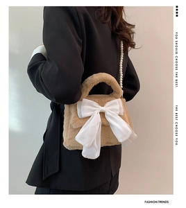 Détail du sac bandoulière en peluche avec nœud blanc et bandoulière en perles