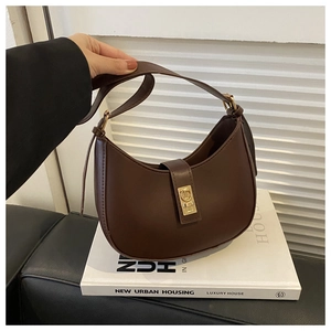 Détail du sac hobo marron avec boucle carrée dorée posé sur un support blanc