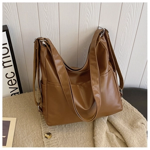 Detail view of large brown faux leather tote bag with wide straps and side pockets