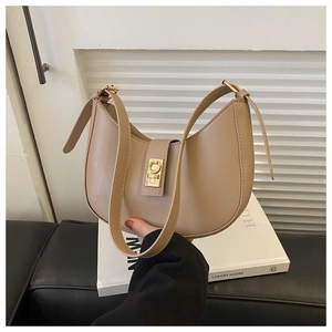 Détail du fermoir doré sur un sac à bandoulière minimaliste beige en forme de croissant