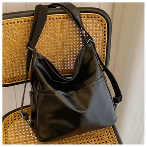 Detail of black leather tote bag with side pocket on a yellow woven chair