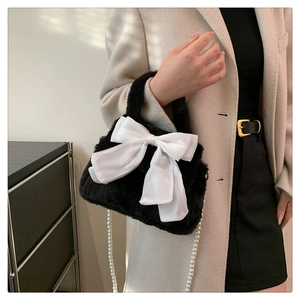 Detail of black plush crossbody bag with white satin bow and pearl chain strap