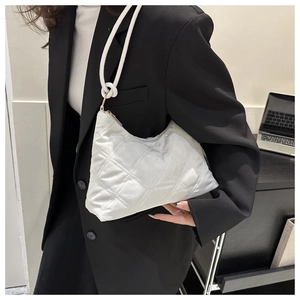 Detail of white quilted nylon shoulder bag with knotted strap on a professional model