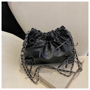 Detail der schwarzen gefalteten Beuteltasche mit Zierschleifen und silberner Kette