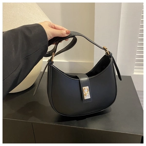Détail d'un sac demi-lune noir avec un fermoir rotatif rectangulaire doré et élégant