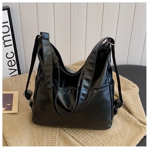 Detail of a large black shoulder bag with two front pockets and adjustable strap