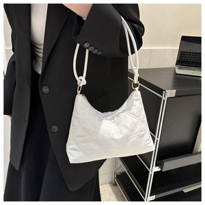 Quilted white shoulder bag with glossy finish and metal rings on a black suit