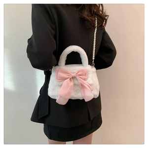 Sac en peluche blanc avec nœud rose et bandoulière en perles porté sur une veste