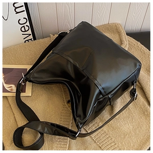 Detailed macro view of matte black PU leather shoulder bag with vertical stitching