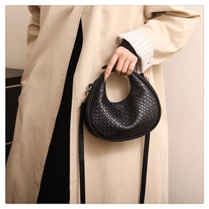 Detail of black woven leather crescent bag with gold hardware and woven texture