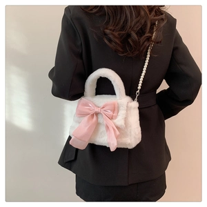 Détail du sac à main en peluche blanche avec nœud rose et bandoulière en perles chics