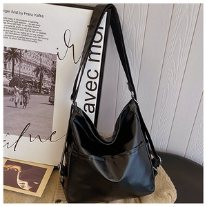 Close-up of black glossy leather tote bag with adjustable metal buckles and front pocket