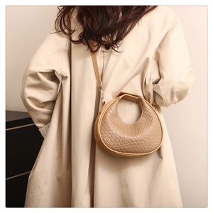 Detailed view of khaki hobo bag featuring woven leather texture and crescent moon silhouette