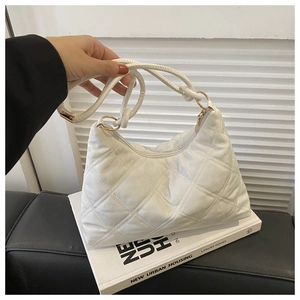 Detailed shot of white quilted hobo bag featuring woven shoulder strap and golden buckle