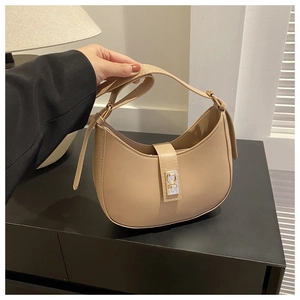 Détail d'un sac bandoulière beige en demi-lune avec une boucle en métal doré chic