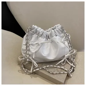 Detail der weißen Kordelzug-Tasche mit Schleifendekor und silberner Gliederkette