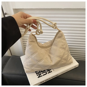 Detail of quilted beige nylon shoulder bag featuring decorative knotted strap and soft texture