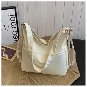 Close-up of ivory tote bag detailing zip closure, side pocket and adjustable shoulder strap