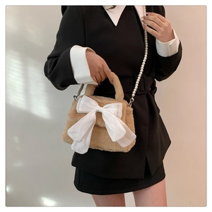 Détail du sac en peluche avec grand nœud blanc et bandoulière en perles élégante