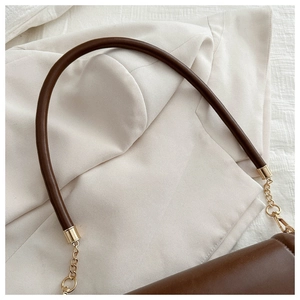 Detailed close-up of brown leather shoulder strap with gold metal buckle and chain hardware