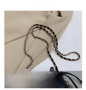 Close-up of gold metal and black leather woven chain strap on quilted bucket bag