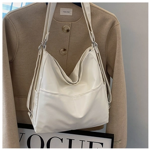Detail of white minimalist faux leather tote bag with symmetrical front pockets on coat