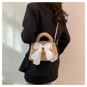 Détail du sac bandoulière en peluche kaki avec grand nœud blanc et bandoulière en perles