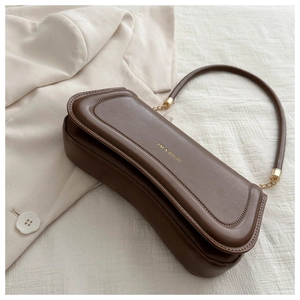 Detail of dark brown leather baguette bag with gold metal buckle and XM & BAGS logo