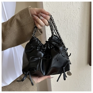 Detail einer schwarzen Lederbeuteltasche mit Faltendesign und einer zarten Schleifenverzierung